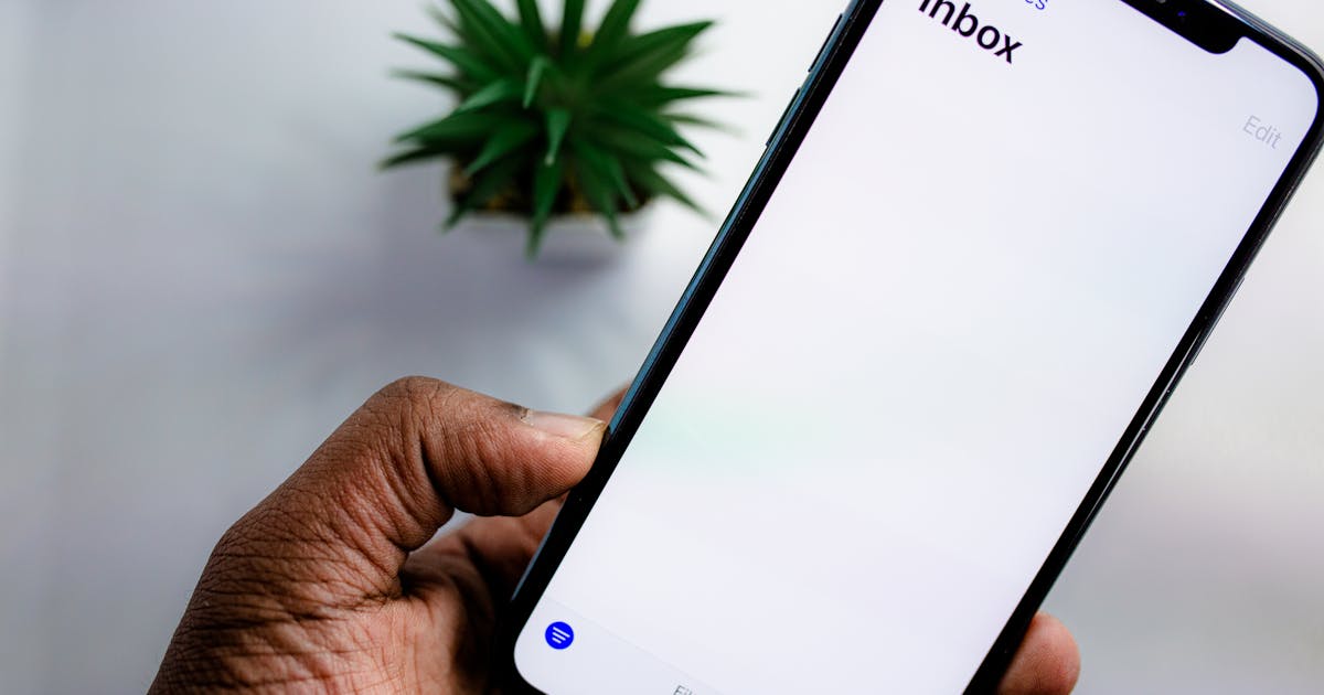 Une main tenant un téléphone affichant une boîte de réception